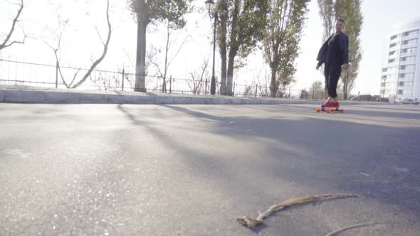 Young Man Skates on His Longboard on the Road in the City