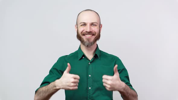 Happy bearded man in shirt showing thumbs sign up over white background. Good job