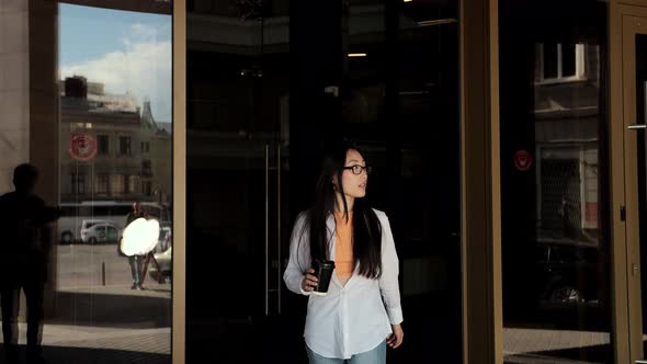 Young Asian Woman Going Out From the Modern Building and Drinking Coffee