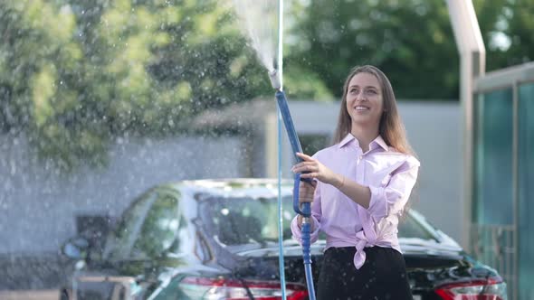 Slim Beautiful Young Woman Spraying High Pressure Water with Jet Smiling Standing on Sunny Day at