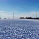 Flying above a snowy field towards a windfarm in Germany. Aerial view of a wind farm. - VideoHive Item for Sale