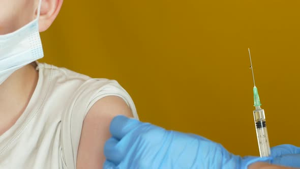 Close-up shot of a 7-8 year old Caucasian boy being vaccinated in the shoulder at the clinic