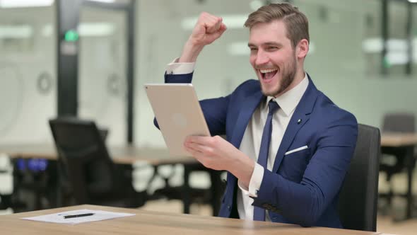 Successful Businessman Celebrating on Tablet at Work