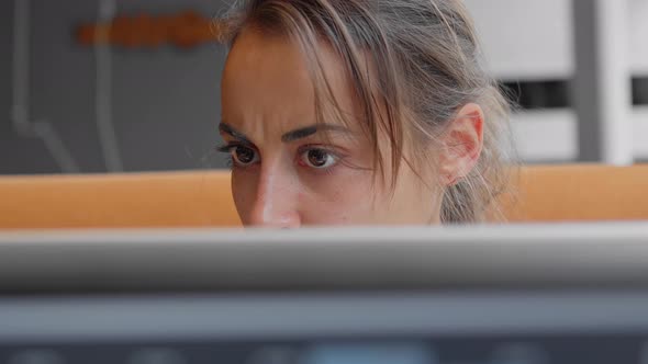 Worried Female Scientist or Laboratory Assistant Looks Attentively and Intently at Monitor