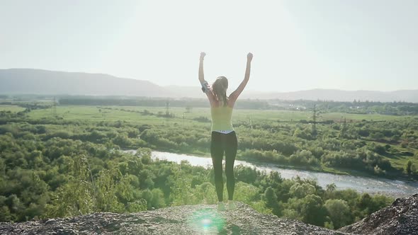 Young Sports Girl Standing on Top of the High Cliff Above the River