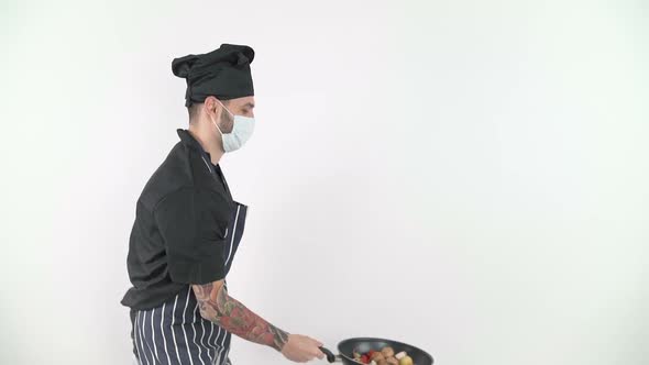 Side View of Young Male Chef Tossing Vegetables From Wok