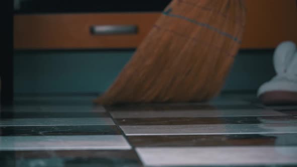 Young Girl Sweeps the Floor in the Kitchen with an Ordinary Broom