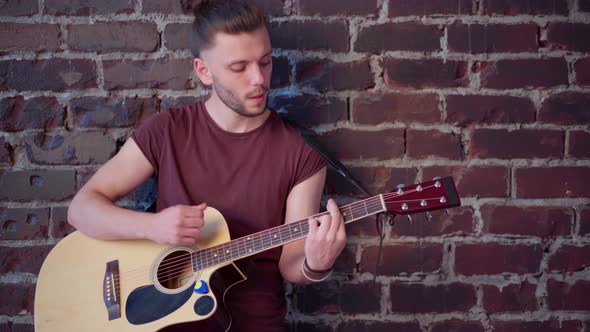 Man with Acoustic Guitar Against Brick Wall Playing Music Singing Songs Enjoy Life Medium Shoot