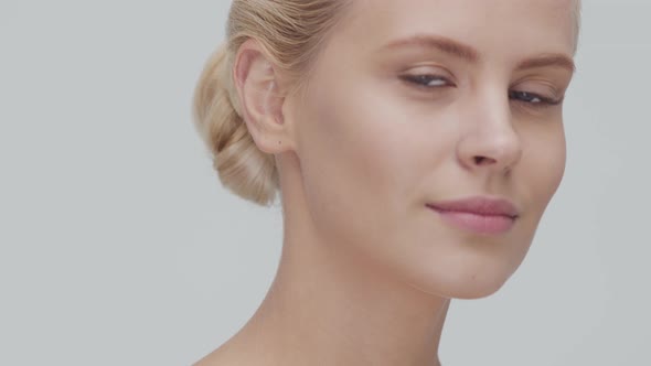 Studio portrait of young, beautiful and natural blond woman applying skin care cream. F