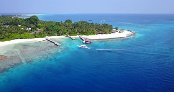 Paradise tropical island with luxurious resort, white sandy beach and piers with docks into small ha