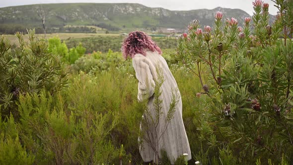 Woman Seen Walking Through Bushy Field