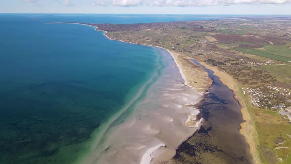 Aerial view flying across the sea in Sejerøbugten with beautiful sandbanks, green hills and amazing