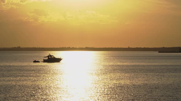 Silhouette of boat and jet ski at sunset in the bay