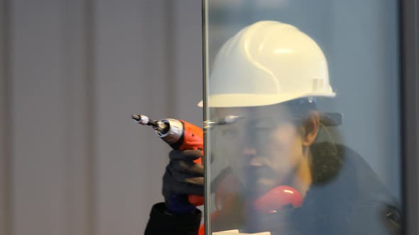 Female technician behind glass pane with drill looking at camera