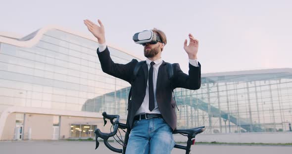 Man in Business Clothes which Leaning on His Bike and Working in Virtual Reality Headset 