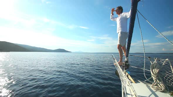 Man standing on the bow of sailing boat on Mediterranean sea.