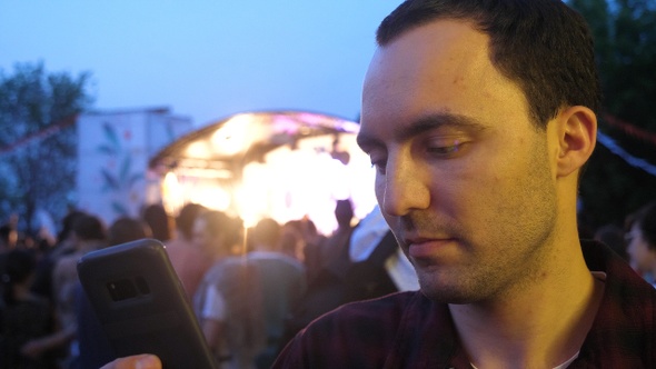 Man using a phone texting a message at concert.