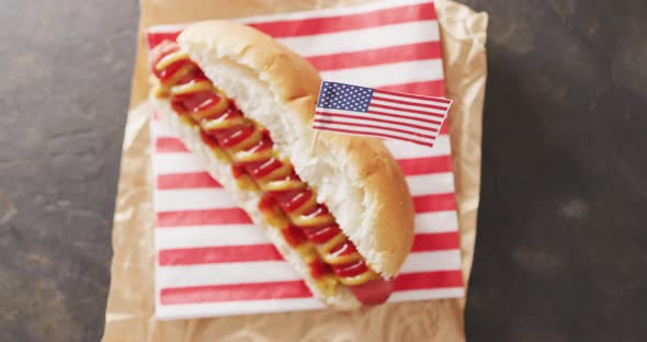 Video of hot dog with mustard and ketchup with flag of usa on a black surface