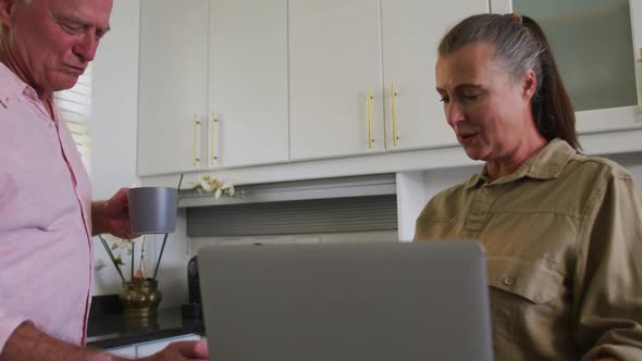 Caucasian senior couple drinking coffee together in the kitchen at home