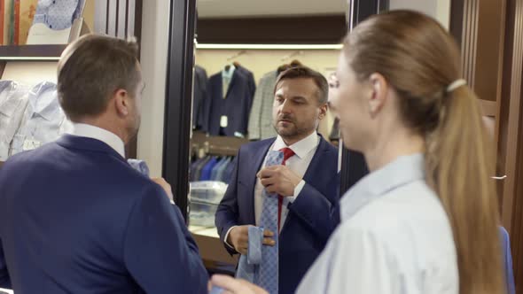 Sales Assistant Helping Man with Choice of Necktie