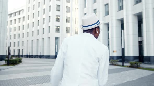 Black man in white wireless headphones sings listening to music