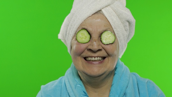 Elderly Grandmother in Bathrobe After Shower. Old Woman with Slices of Cucumber