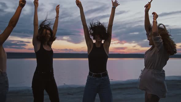 Millennial Women Celebrating Sunset Dancing on Beach with Fireworks