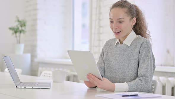Cheerful Young Latin Woman Celebrating Success on Tablet 