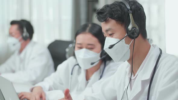 Man And A Woman Doctors Wearing Headsets And Masks Working As Call Centre Agent Discussing Work