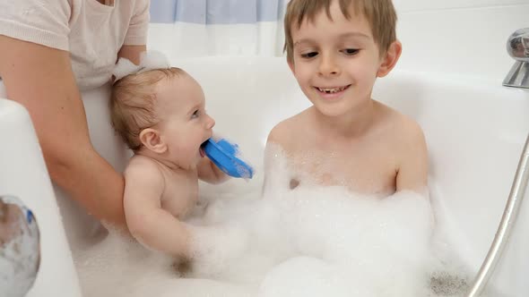 Cute Baby Boy and Older Brother Washing and Playing in Bath with Foam