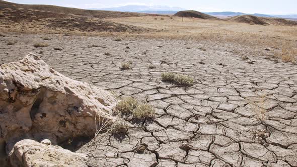 Panning over dry desert landscape with cracks in the soil