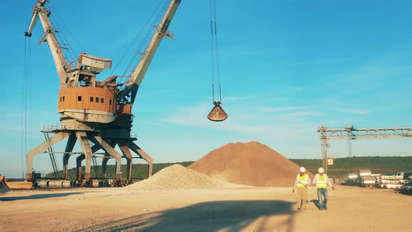 Male Workers Are Passing By the Cranes Unloading Rubble