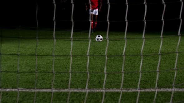 Soccer player scoring a goal against open goal post