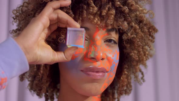 Mixed Race Woman with Curly Hair and Bright Neon Makeup Pattern on the Face the Same Like on Her