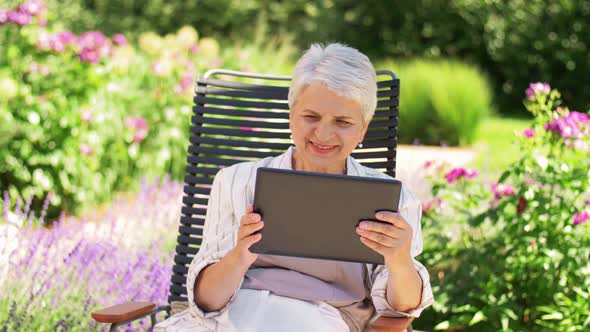 Happy Senior Woman with Tablet Pc at Summer Garden