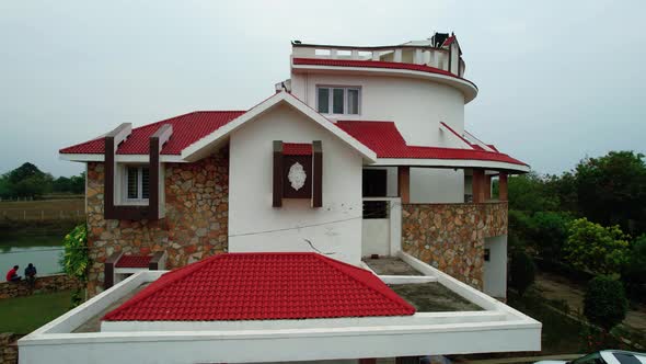 Red tiled roof on a white house with windows, stairs and ocher stones. The sky is light blue and cle