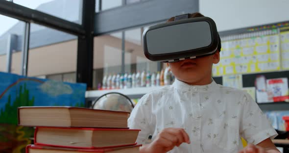 Front view of Asian schoolboy using virtual reality headset in classroom at school 4k