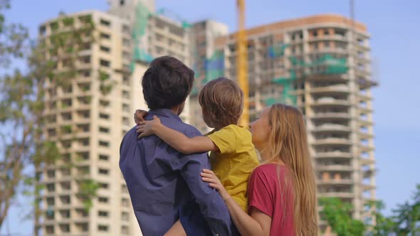 A Family Father Mother and Son Look at a Tall Building That is Under Construction