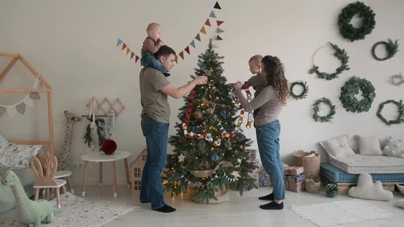 Young Family of Four Decorating Christmas Tree