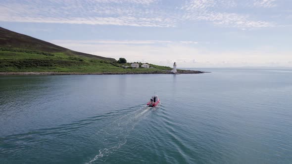 A Small Cargo Ferry at Sea Motoring Alongside an Island