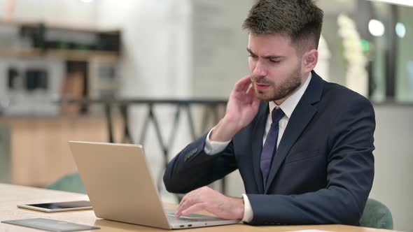 Hardworking Young Businessman with Laptop Having Back Pain in Office