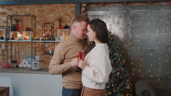 Lovely Couple Dancing Near the Christmas Tree and Drinking Champagne.