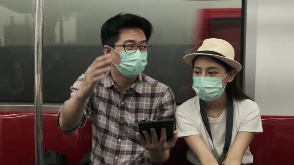 Young couple Asian tourists search travel locations by a tablet in train cabin.