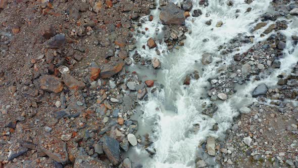 A Topdown Aerial View of a Stormy Mountain Stream Among Multicolored Stones