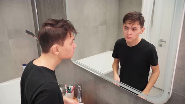 Handsome Young Man in Hearing Aids Washes Foam Off His Face in a Skincare Bathroom