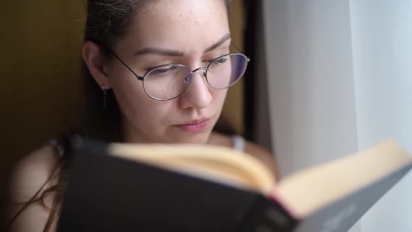 young woman is reading a book, view from behind a book, close-up