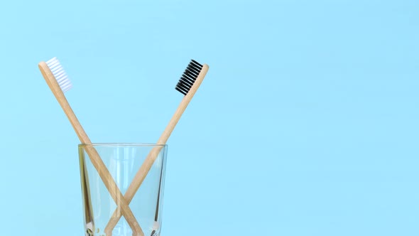 Two bamboo toothbrushes rotating in glass