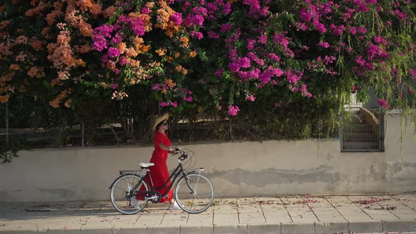 Wide Shot Street with Blooming Trees and Young Woman in Red Dress Passing with Bicycle in Slow