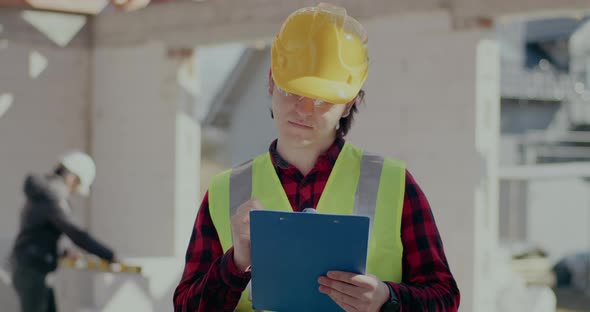 Confident Male Contractor Writing on Clipboard