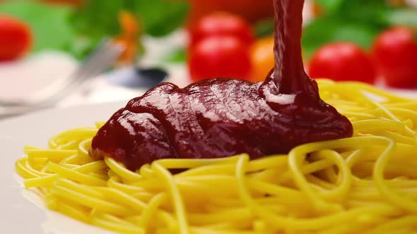 Pouring ketchup on spaghetti, tomato sauce falling on pasta, slow motion